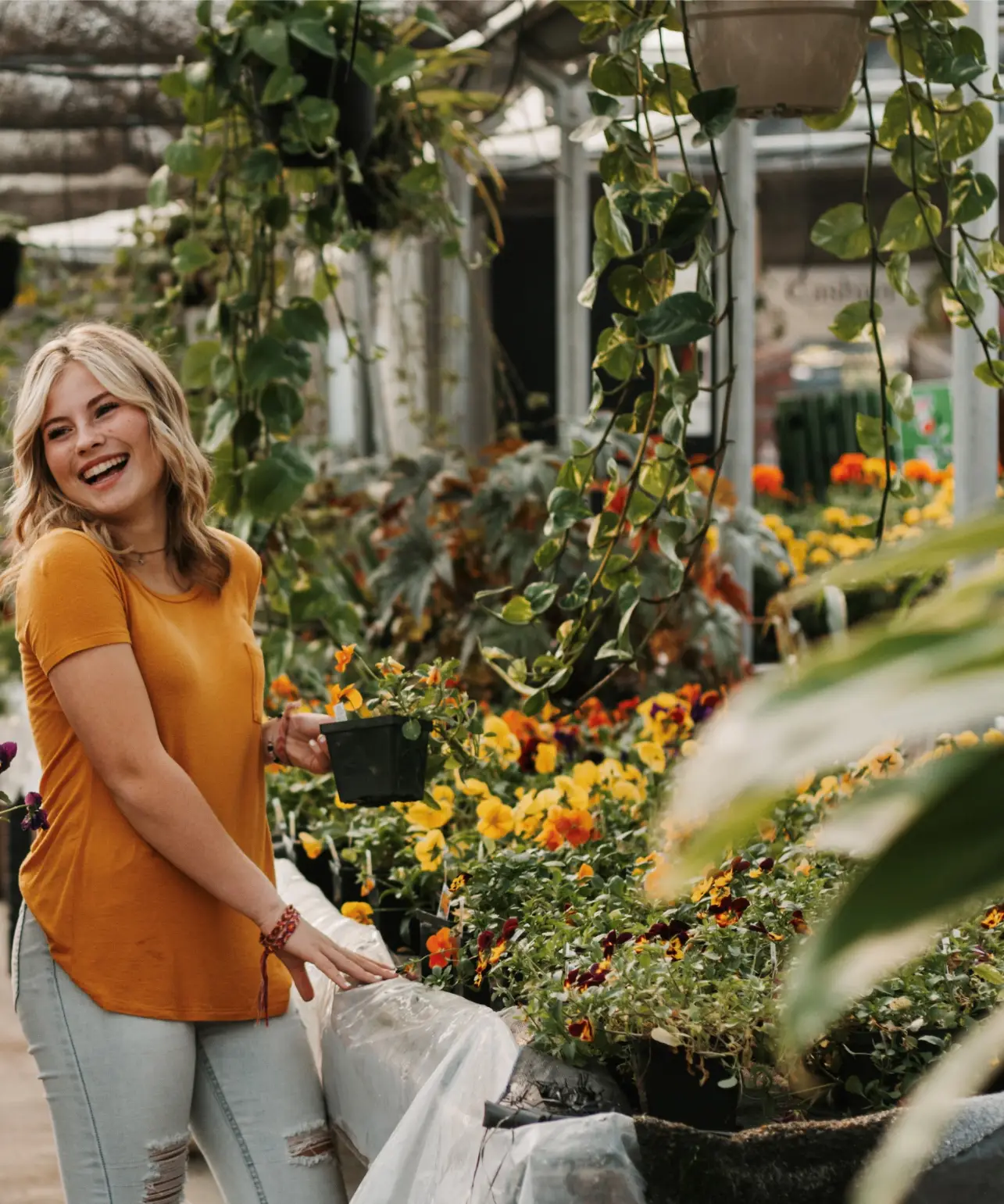 Smiling patient holding a potted flower in a greenhouse