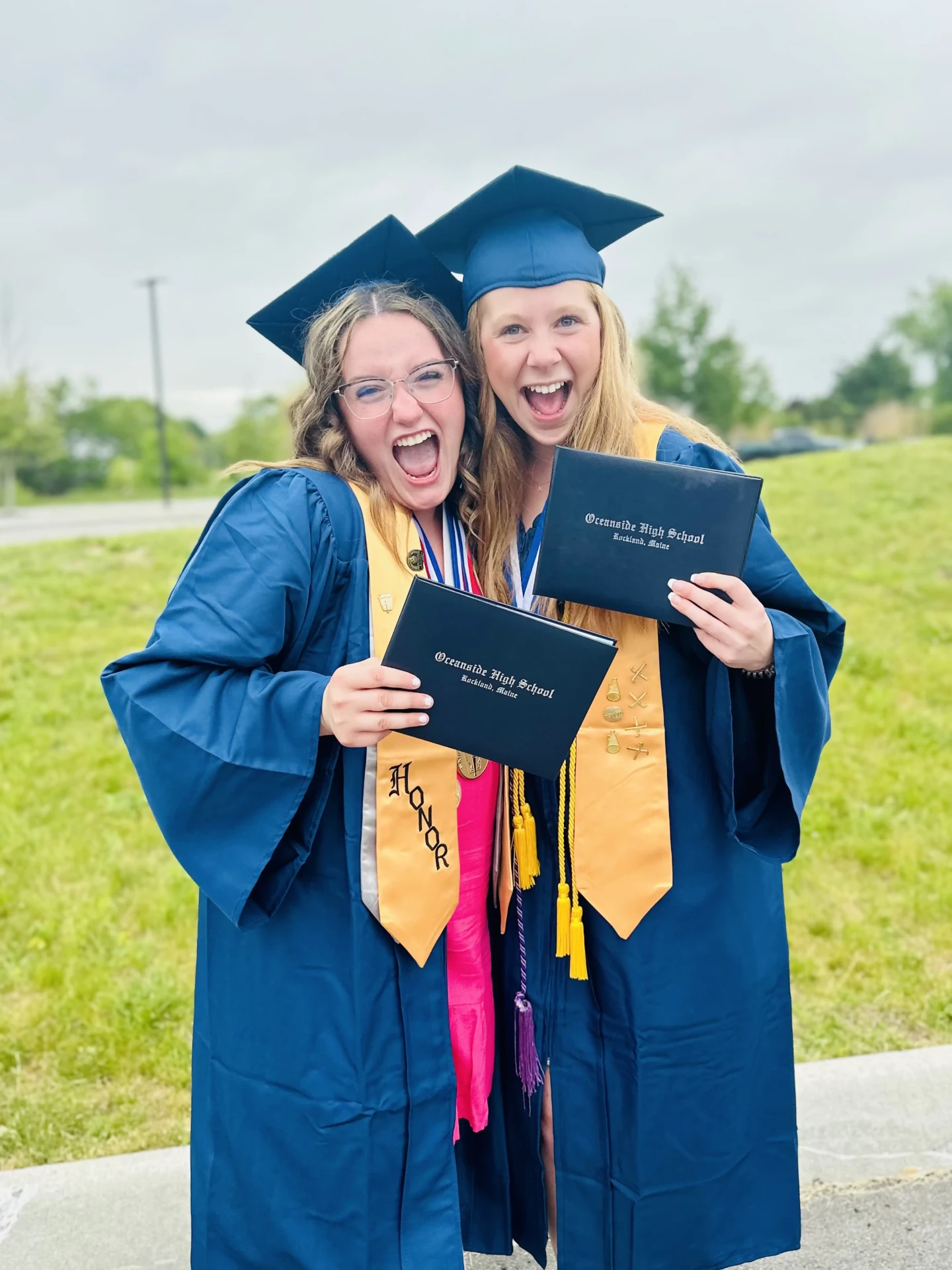 Two graduates cheering with their high school diplomas