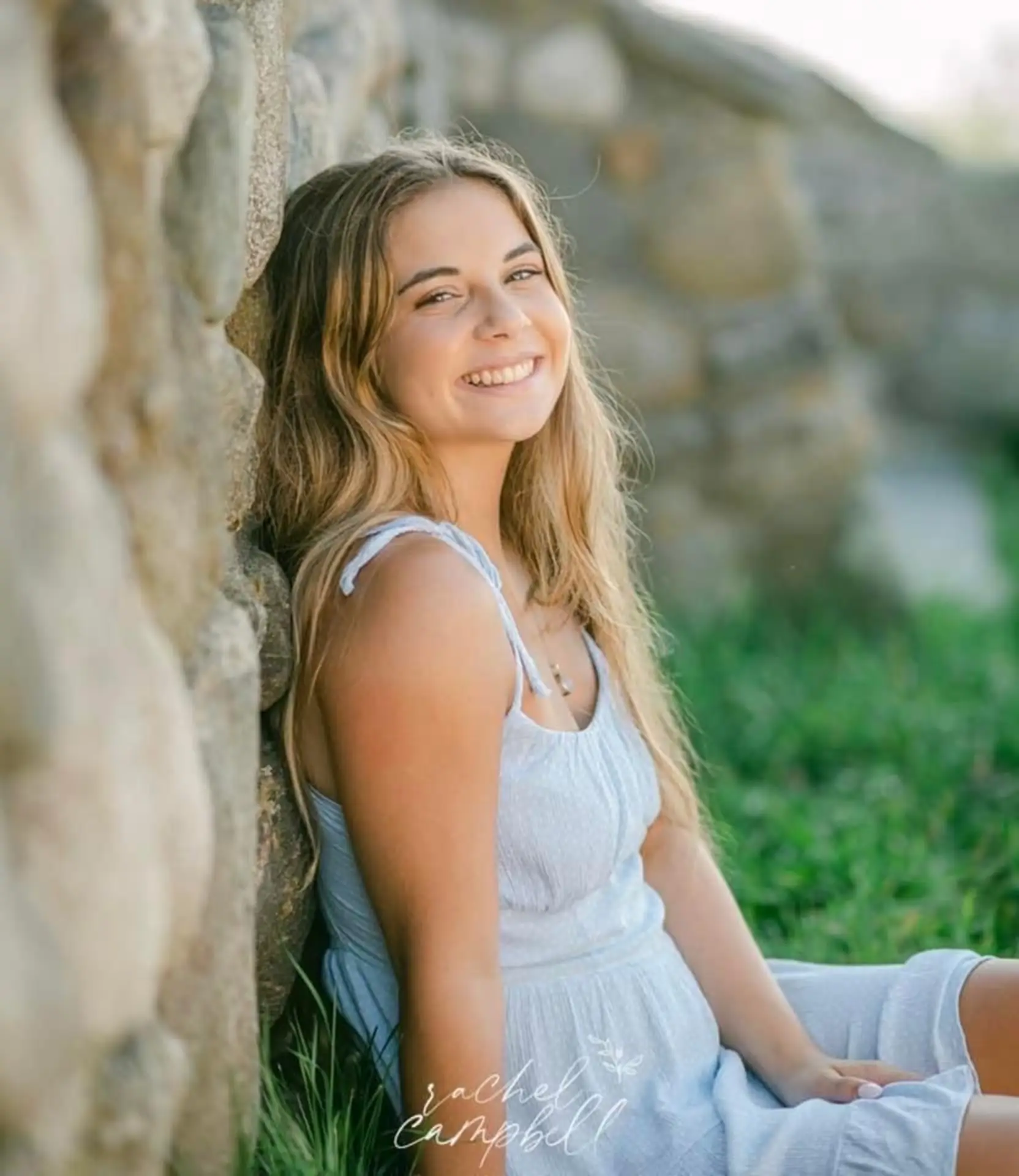 Smiling patient sitting beside a stone wall outdoors