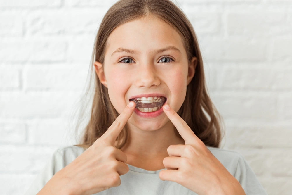 Child smiling with a clear orthodontic appliance