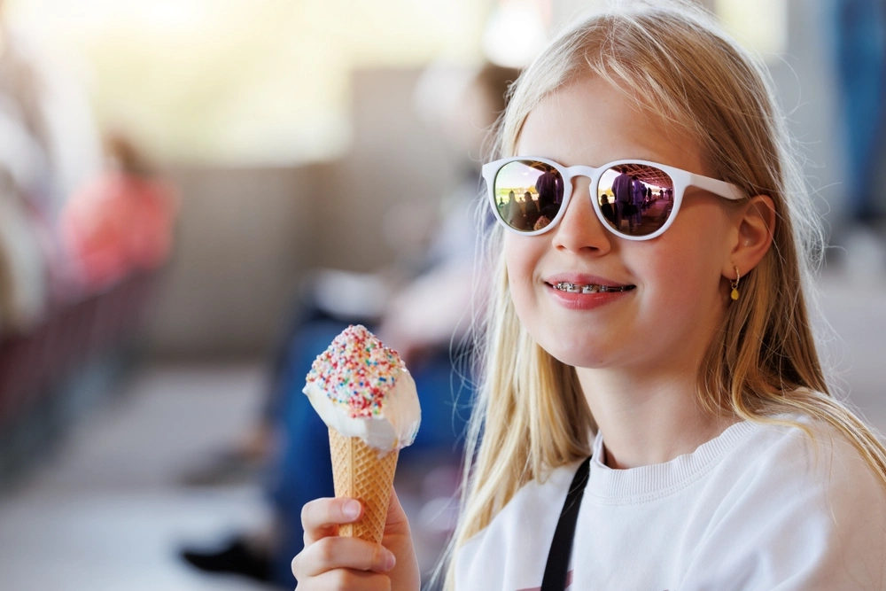 Child smiling with braces and an ice cream cone