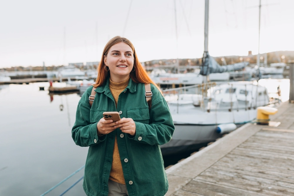 Person standing by a harbor with a phone