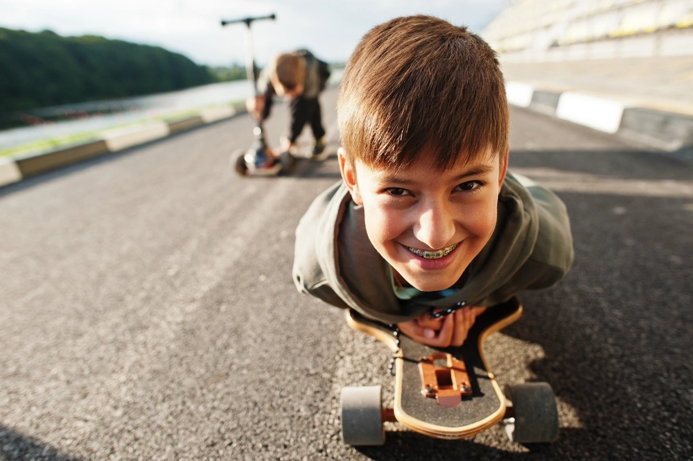 Child smiling with braces while skateboarding